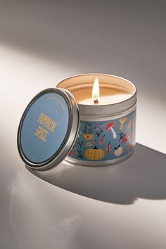 an empty tin candle sitting on top of a white table next to a blue box