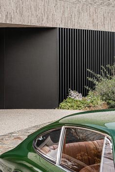 a green car parked in front of a building with a clock on it's side