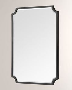 a mirror hanging on the wall with a black frame and silver trim around it's edge