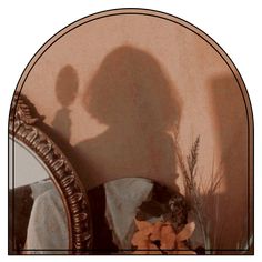 the shadow of a person standing in front of a mirror next to a vase with flowers