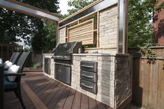 an outdoor kitchen with grill and seating area