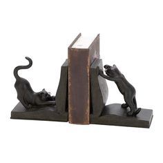 two black cats playing with each other on top of a bookend that is made out of wood