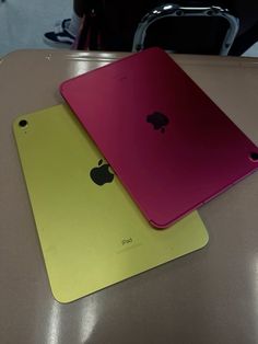 two different colored ipads sitting next to each other on top of a table in a room