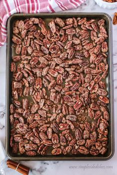 pecans on a baking sheet ready to be baked in the oven with cinnamon sticks