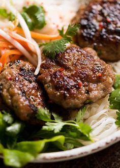 some meatballs and vegetables are on a white plate with noodles, coleslaw and carrots