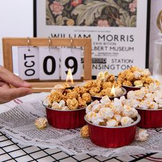 a table topped with red cups filled with popcorn and marshmallows next to a clock