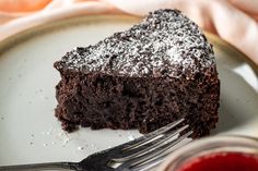 a piece of chocolate cake with powdered sugar on top and a fork next to it