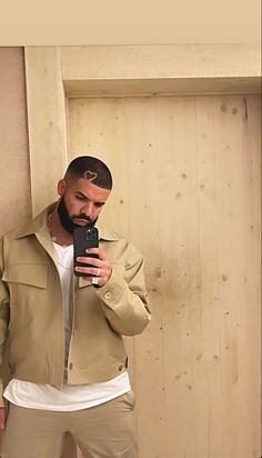 a man taking a selfie in front of a wooden wall with his cell phone