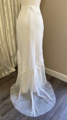 a white wedding dress on display in front of a curtain