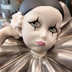 a close up of a doll wearing a silver dress