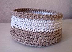 a crocheted basket sitting on top of a table next to a white vase