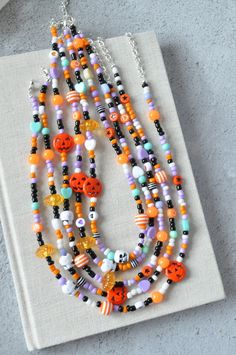 an orange and white beaded necklace on top of a piece of paper next to a pair of scissors