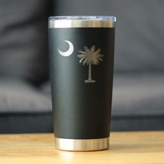 a black and silver tumbler cup sitting on top of a wooden table next to a couch