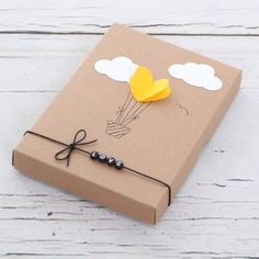 a brown box with a yellow balloon on it sitting on a white wooden table next to a string