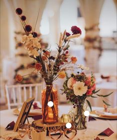 two vases filled with flowers sitting on top of a white tablecloth covered table