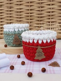 two knitted baskets sitting on top of a table next to some white and red balls