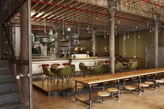 an empty restaurant with wooden tables and green chairs in the foreground is a bar