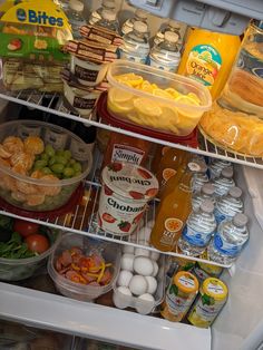 an open refrigerator filled with lots of food and condiments on the bottom shelf