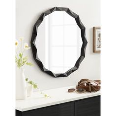 a round mirror hanging on the wall above a dresser