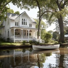 a boat is sitting on the water in front of a white house with trees around it