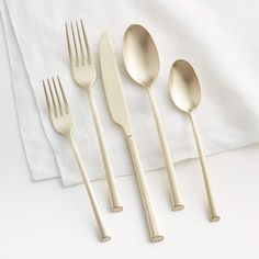 four forks, two spoons and one knife on a white table with a napkin