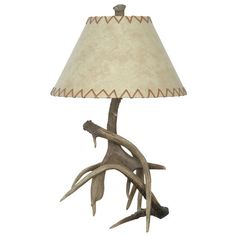 an antler lamp with a beige shade on it's base and a white background