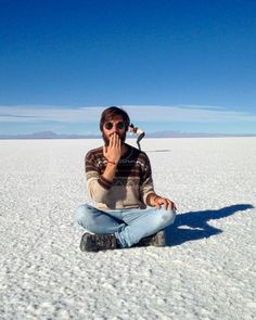 a woman sitting on the ground talking on her cell phone in the middle of nowhere