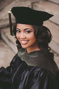 a woman wearing a graduation cap and gown posing for a photo in front of stairs