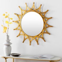 a mirror sitting on top of a white table next to a vase with yellow flowers