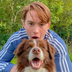 a man holding a brown and white dog in front of him with his mouth open