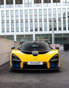 a yellow and blue sports car parked in front of a building