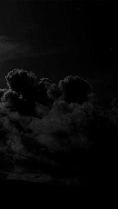 black and white photograph of clouds in the sky with a full moon behind it on a dark night