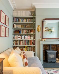 a living room filled with furniture and a fire place in front of a book shelf