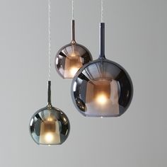 three lights hanging from the ceiling in different shapes and sizes, with one light turned on