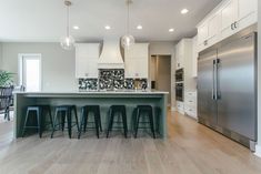 a kitchen with white cabinets and bar stools next to an island in the middle