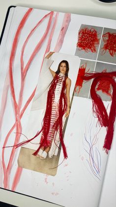 a woman is standing in front of an open book with red thread on the pages