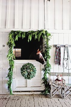 there is a horse that is standing in the stable with wreaths on it's head