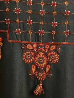 an embroidered shirt with tassels and beads on the neckline is shown in close up