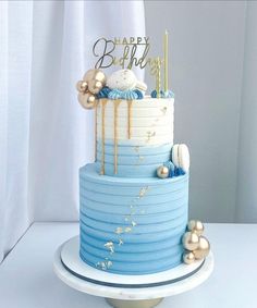 a blue and white birthday cake with gold decorations