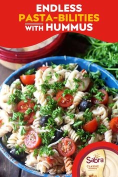 a blue bowl filled with pasta salad next to some parsley on top of a wooden table