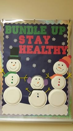 a bulletin board with three snowmen and the words bundle up stay healthy on it