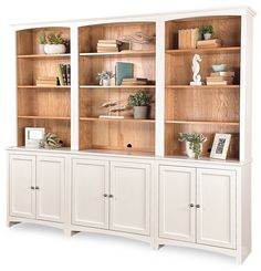 a white bookcase filled with lots of books next to a vase and potted plant