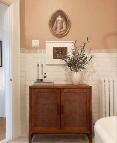 a bathroom with a wooden cabinet and white bathtub next to a painting on the wall