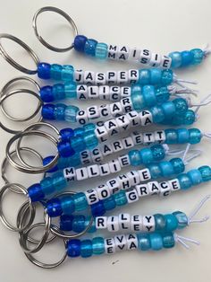 six blue and white bottle openers with names on them, all in the shape of letters