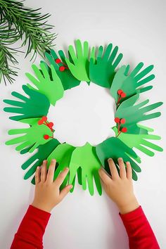 two children are making paper wreaths with green hands and ladybugs on them