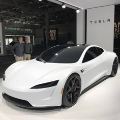 two men standing next to a white sports car