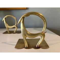 two metal sculptures sitting on top of a white table