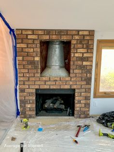 a brick fireplace being installed in a room with plastic covering around it and tools on the floor