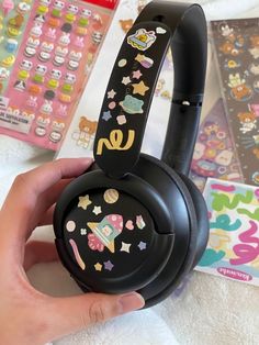 someone is holding up their headphones with stickers on them and there are other items in the background