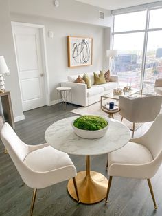 a living room filled with furniture and a white table topped with a bowl of green stuff